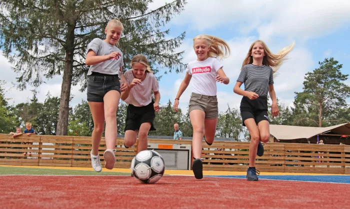 Vier meisjes voetballen op pannaveld